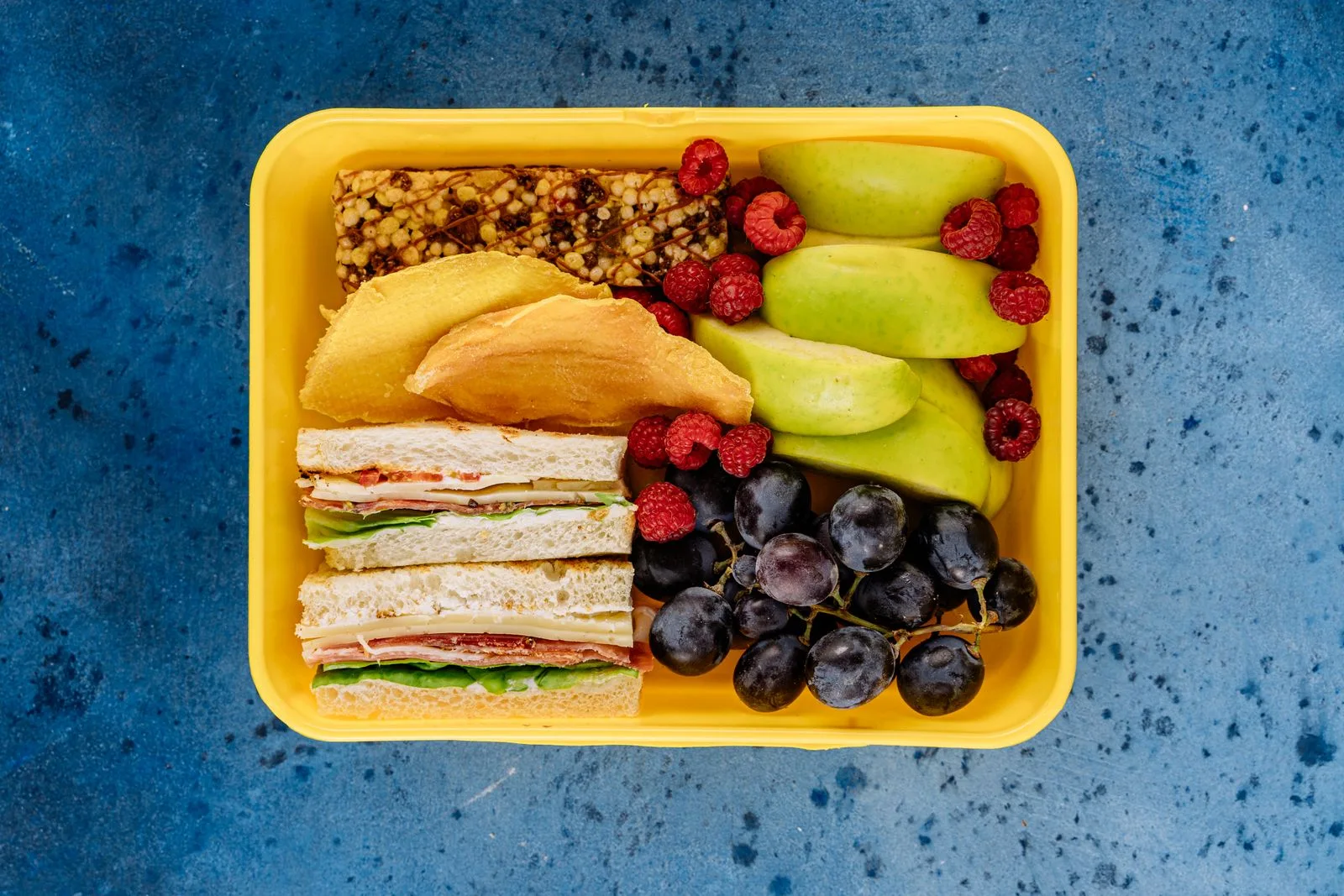 A lunch box filled with sandwiches and fruit