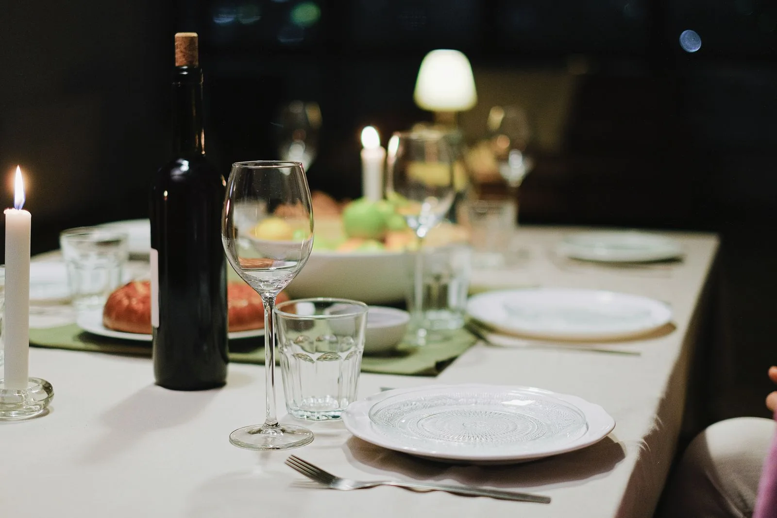 A dinner table set with plates, glasses and candles